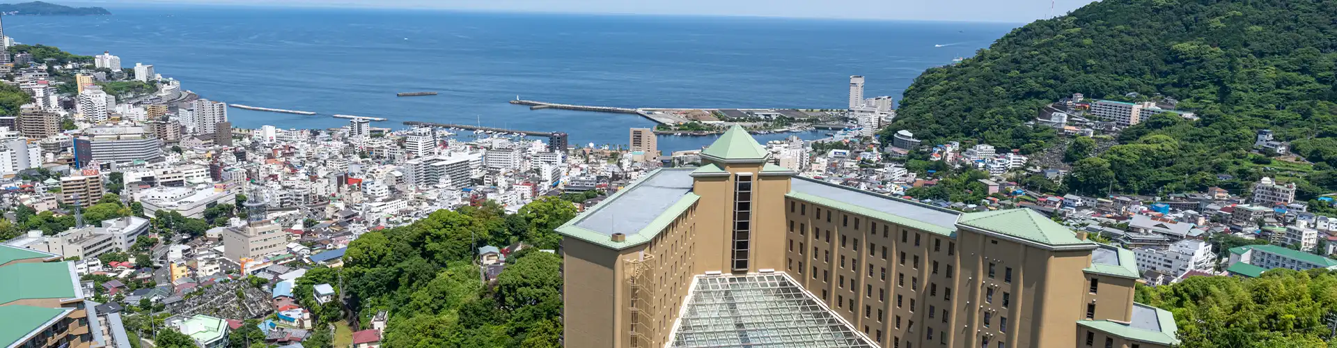 Aerial view of Kamenoi Hotel Atami perched on a hillside above Atami town and Sagami Bay