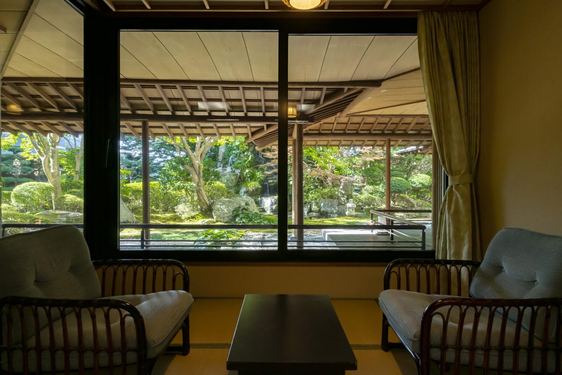 Tatami guest room with low table and chairs overlooking the Japanese garden at Kinugawa Grand Hotel Yume no Toki