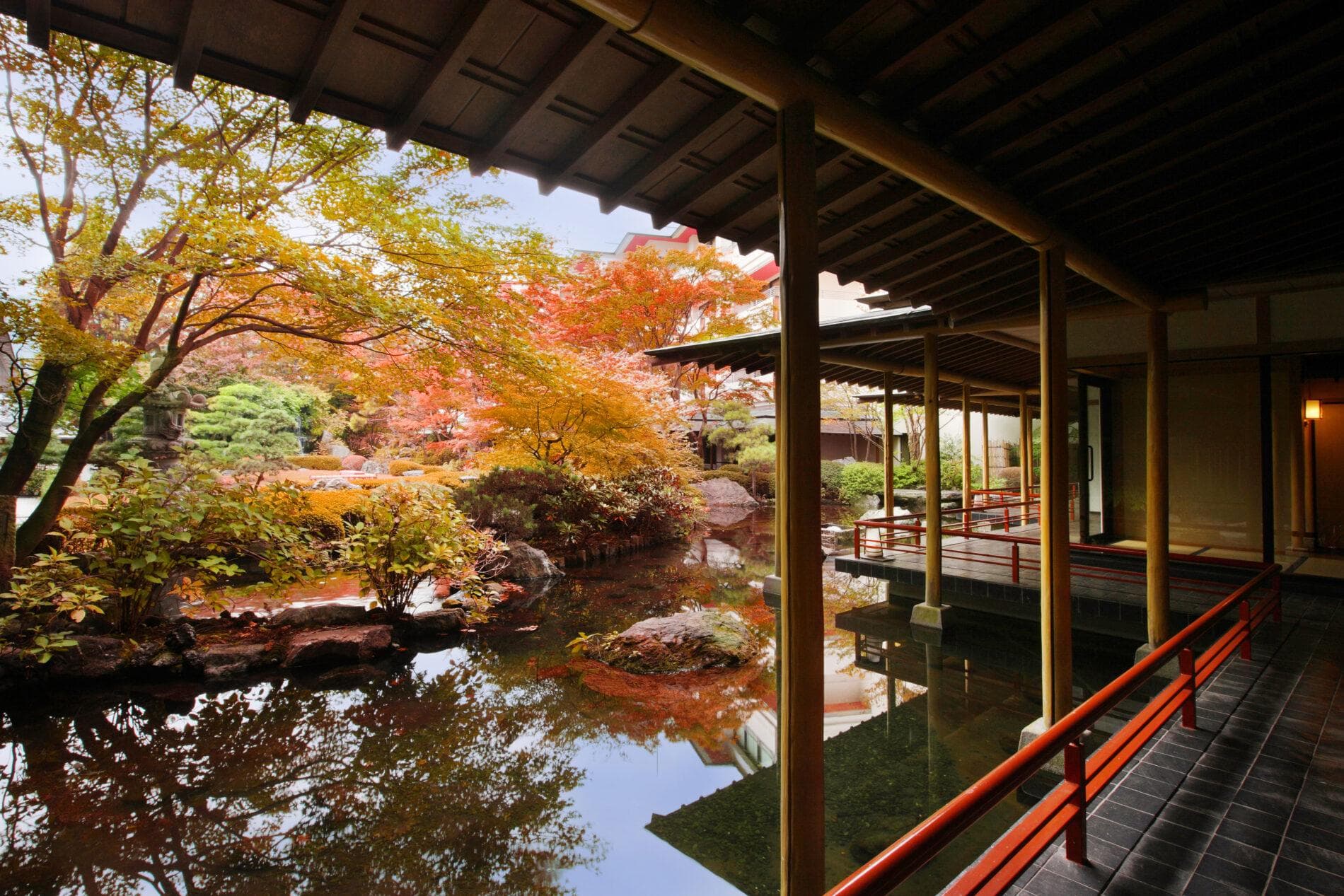 Japanese garden with reflecting pond, autumn maples and wooden engawa corridor at Kinugawa Grand Hotel Yume no Toki