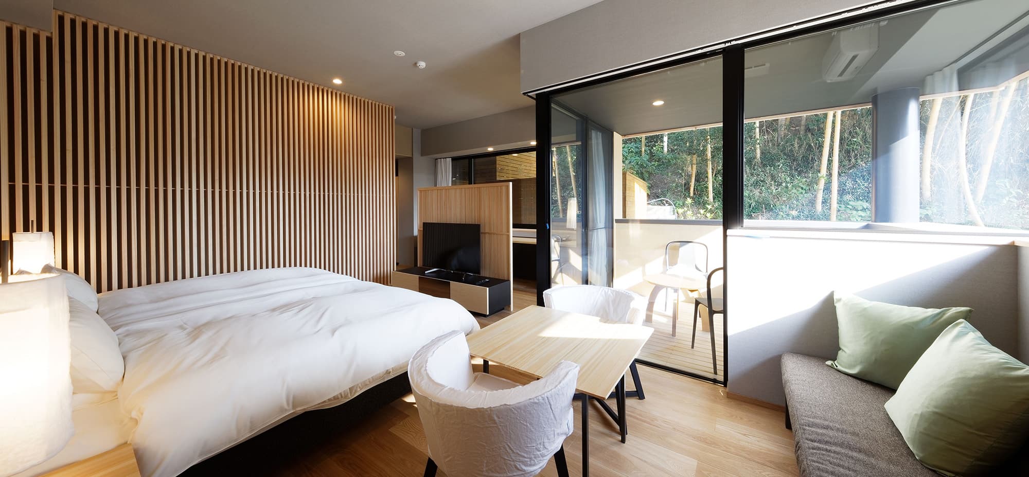 Modern guest room at Koto no Niwa with low bed, lounge sofa and private terrace overlooking forest