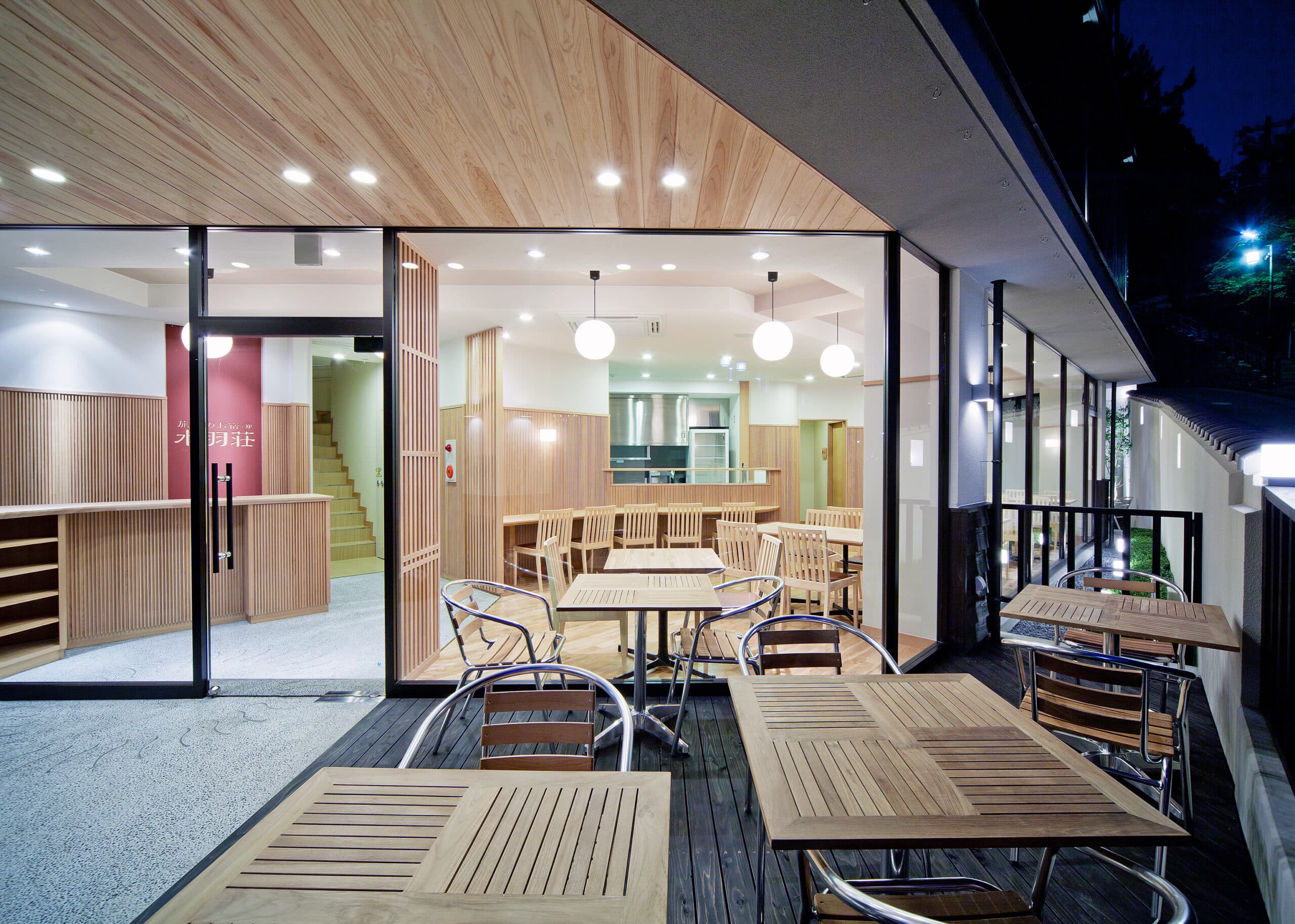 Wooden terrace dining deck at Mizuhaso with cafe tables overlooking the surrounding trees at dusk
