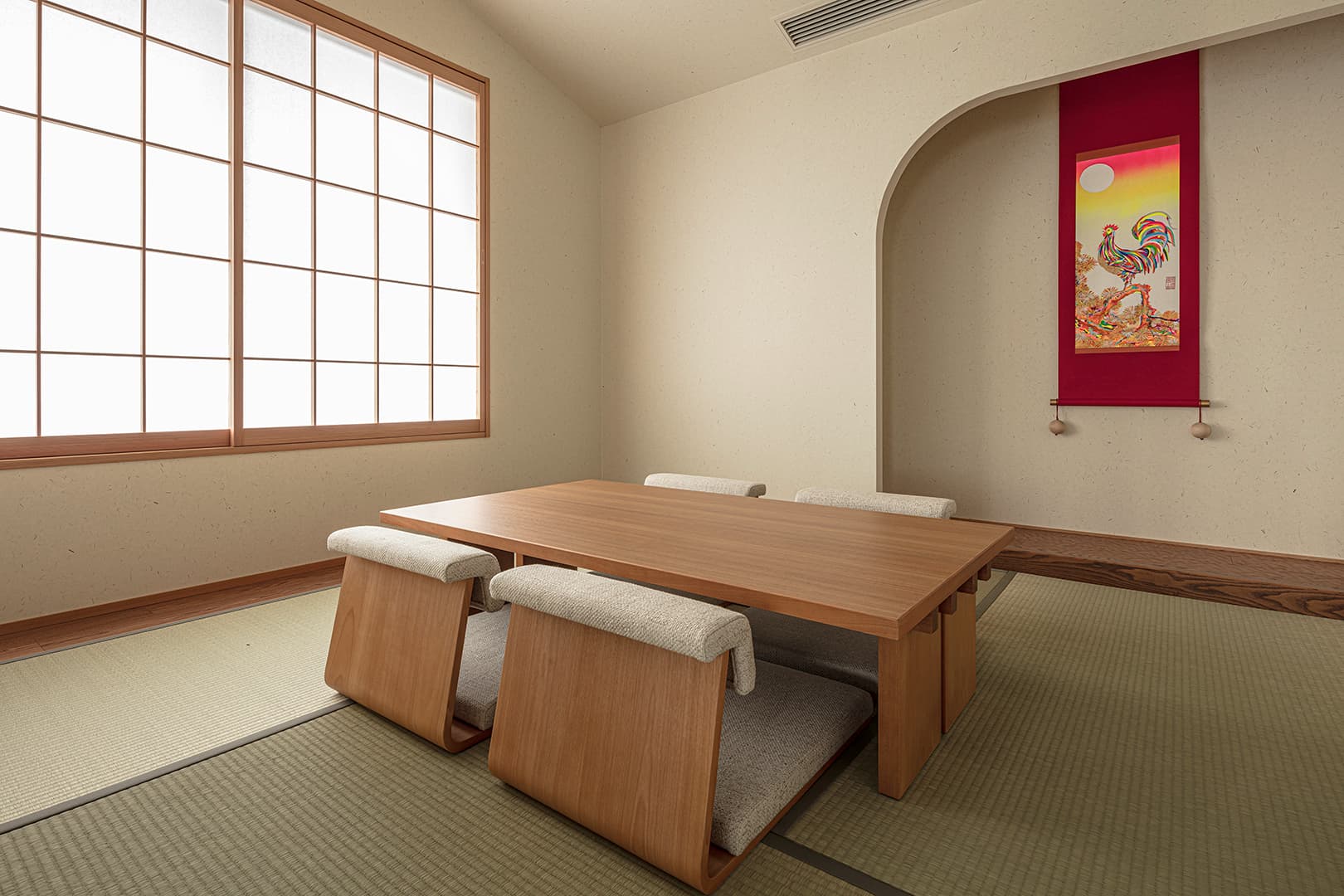 Private tatami dining room at Ohana with a low wooden table, cushioned chairs and an arched alcove holding a colorful hanging scroll