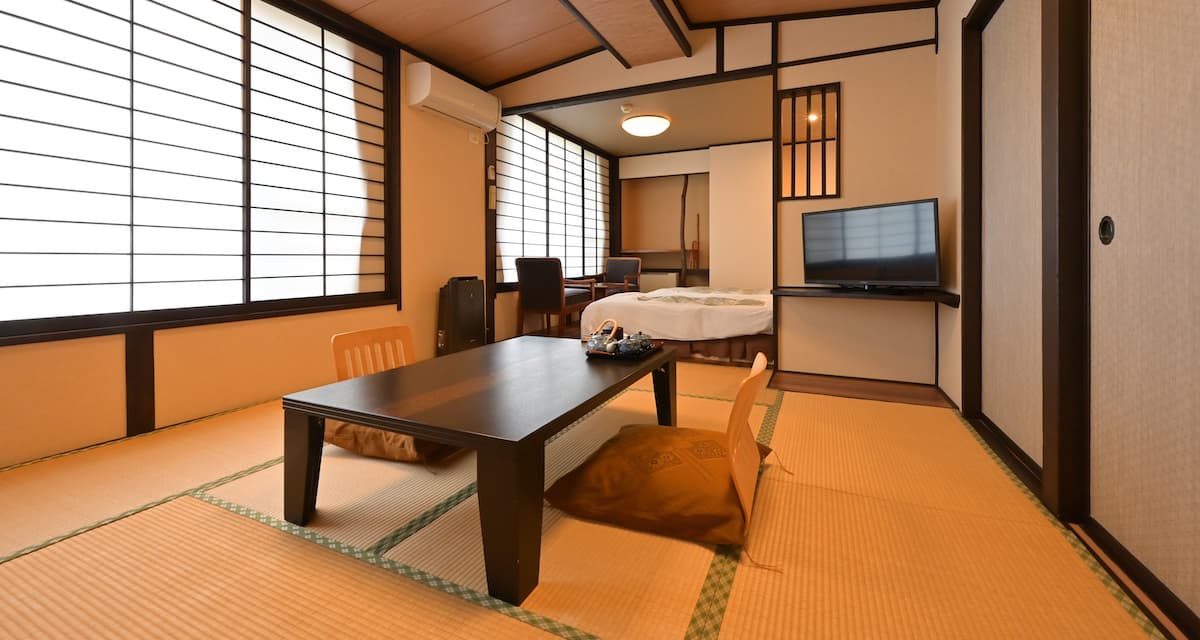Japanese tatami guest room at Ryokan Tamura with shoji screens, a low table and a futon laid out at the rear