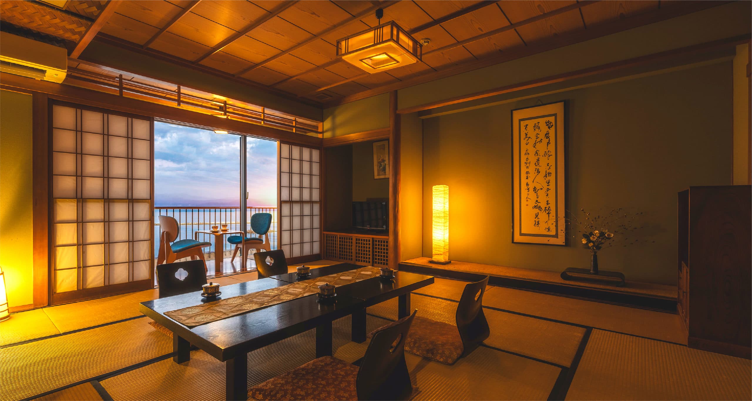 Japanese-style tatami guest room with hanging scroll and sea-view balcony at dusk, Hotel Shougetsu Ibusuki
