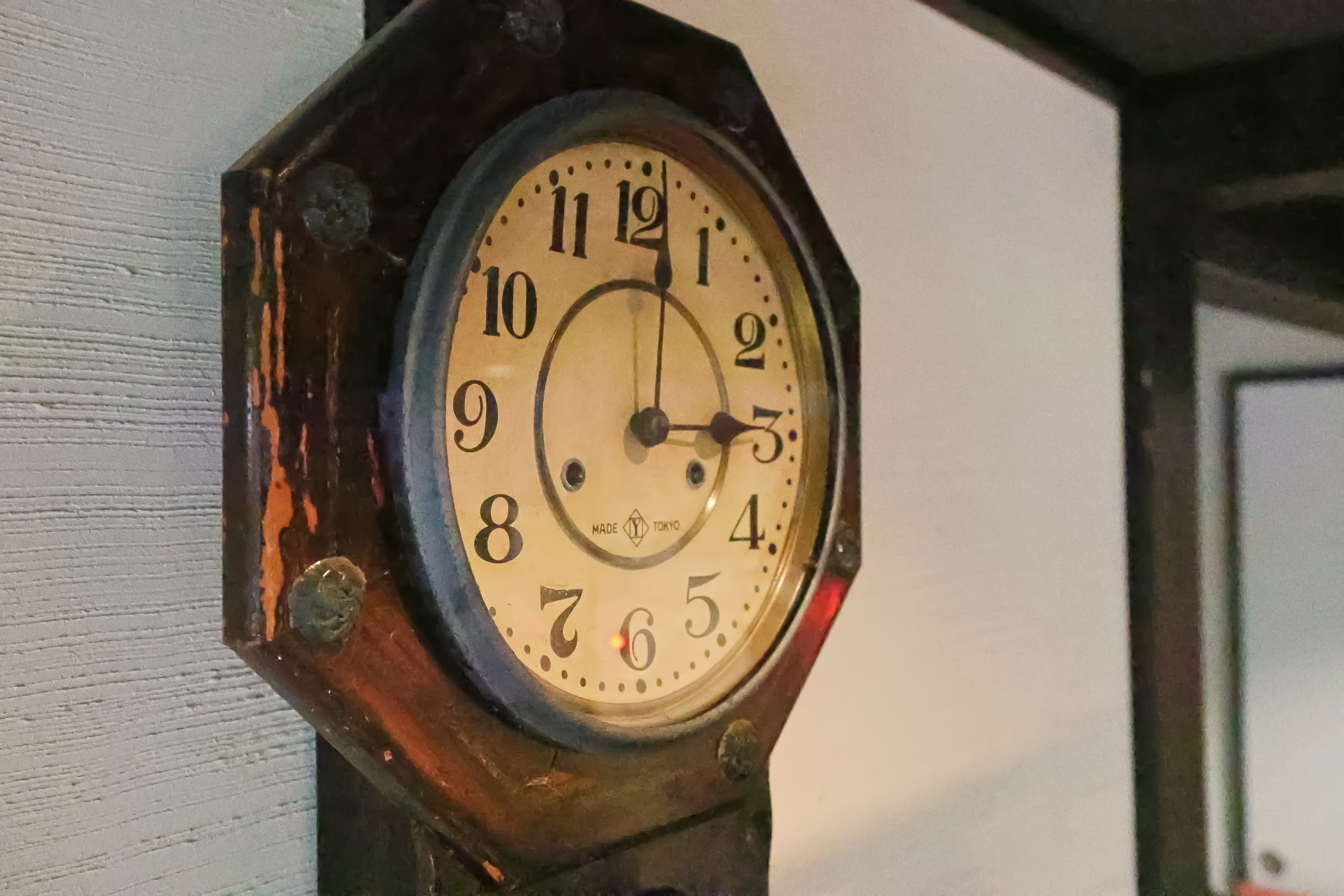 Antique octagonal pendulum clock made in Tokyo mounted on a white pillar
