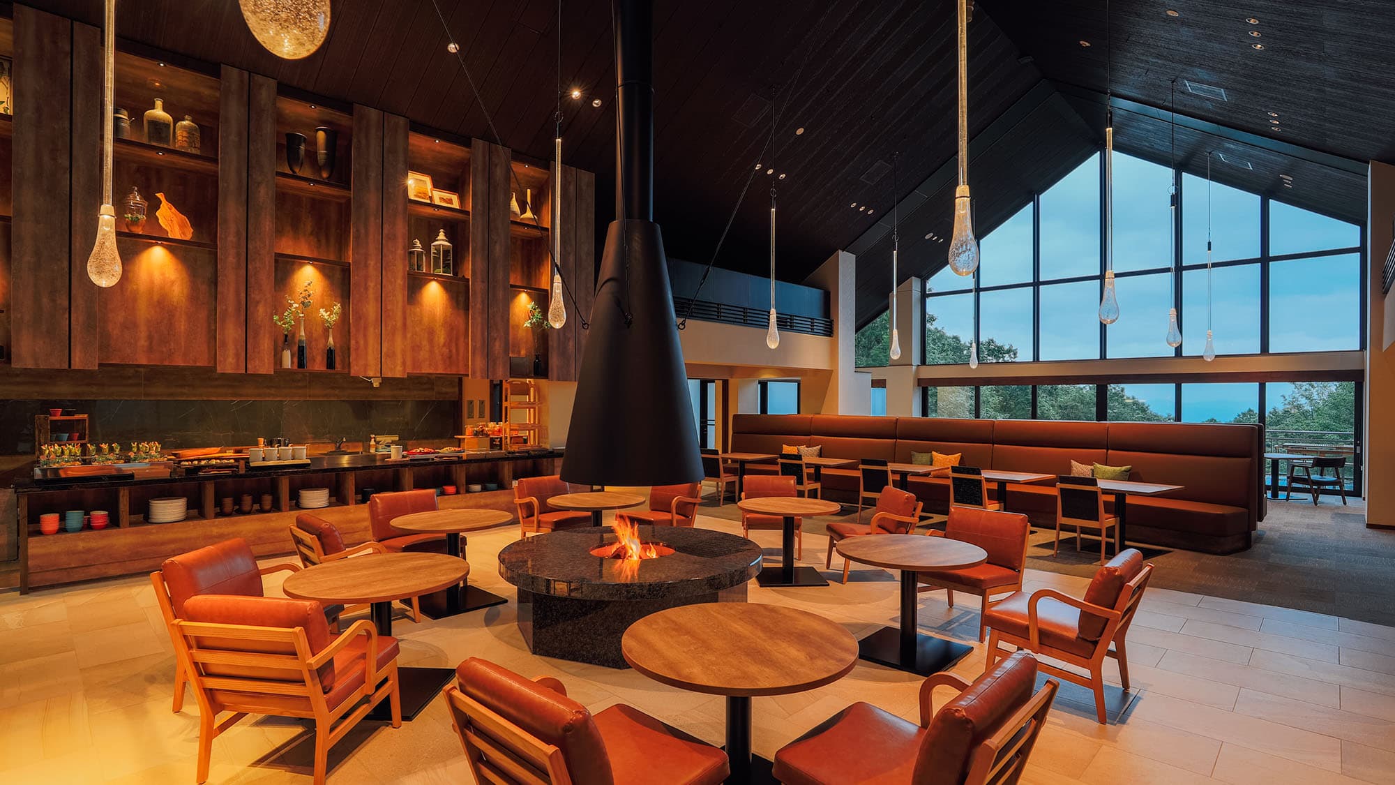 Restaurant lounge with central fireplace and forest windows