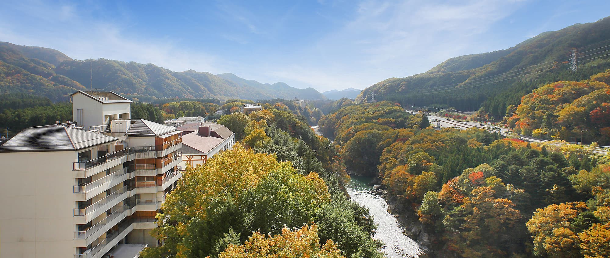 Hotel Tsuga no Ki perched above the autumn-colored Kinugawa Onsen river gorge under a clear sky
