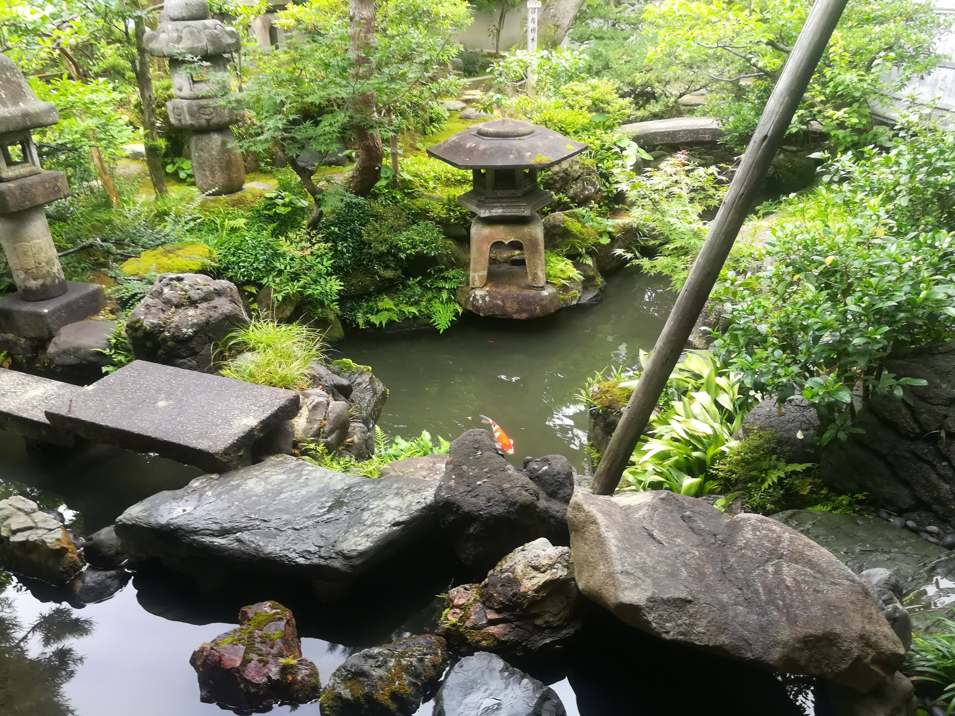 traditional Japanese ryokan garden in autumn, red maple leaves framing a stone lantern and wooden veranda, Iwate Prefecture Tohoku