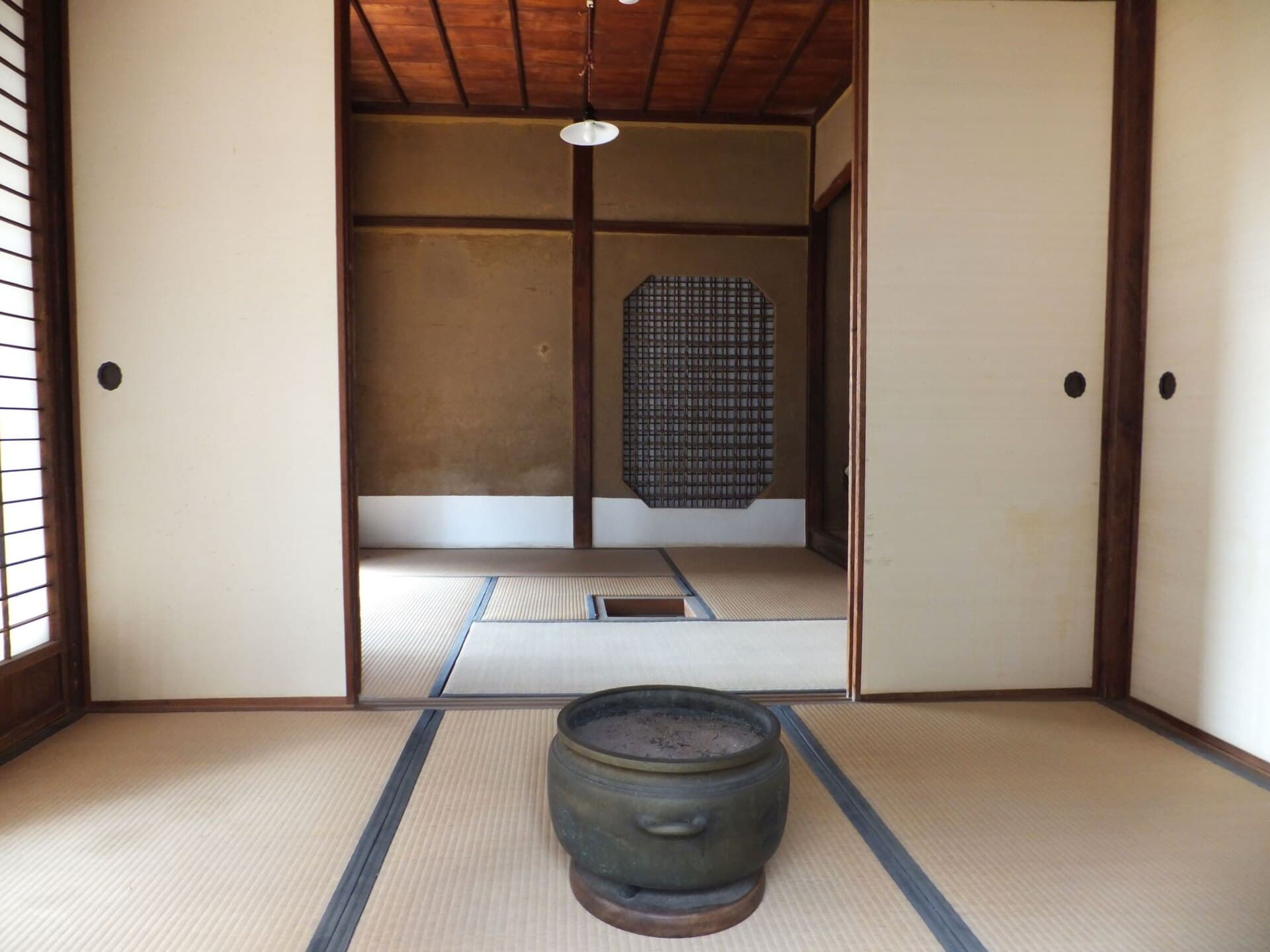 Traditional Japanese tatami room with low lacquer table, shoji screens, and a garden view beyond — the intimate scale of a single-occupant ryokan room