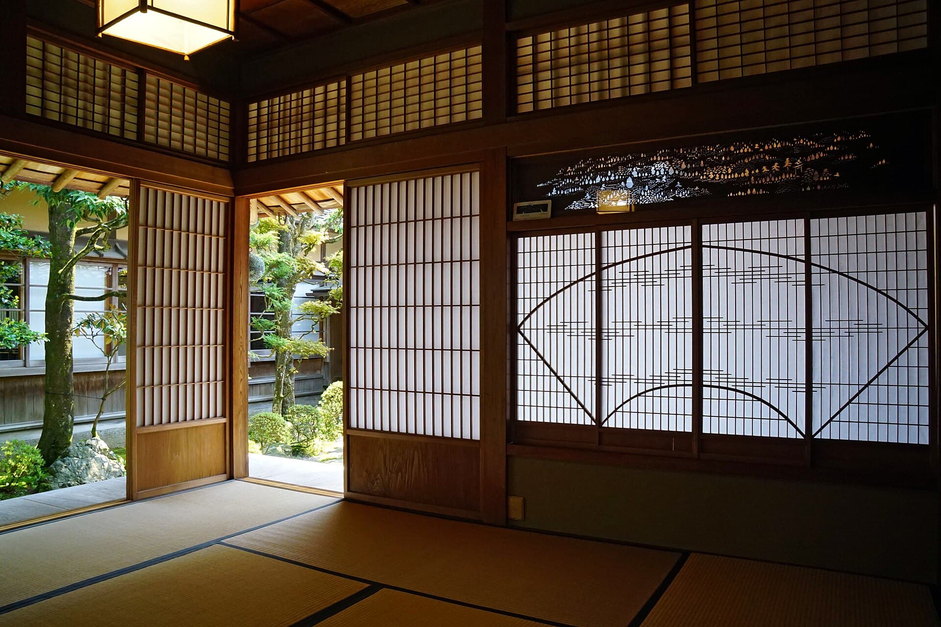 Traditional Japanese tatami room with shoji screen panels and low wooden furnishings, soft natural light from garden-facing windows