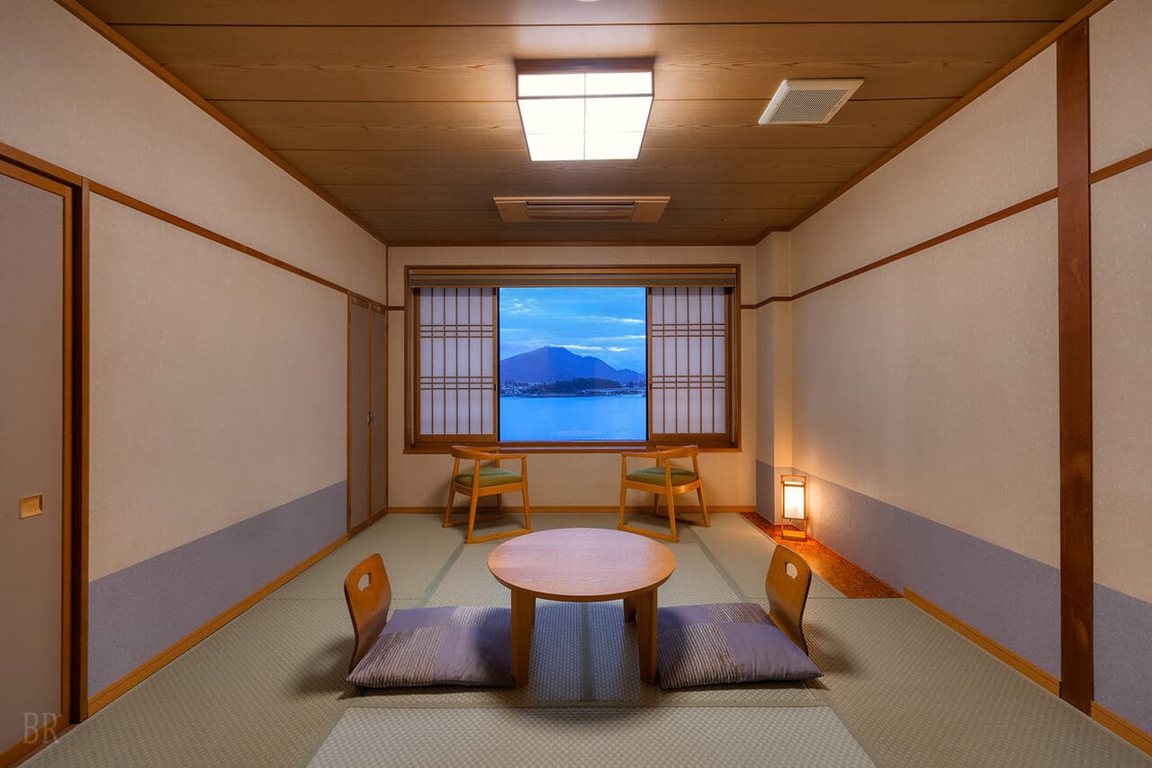 Japanese-style tatami guest room at Hotel Asafuji with a low table and a window framing Lake Kawaguchi and the mountains