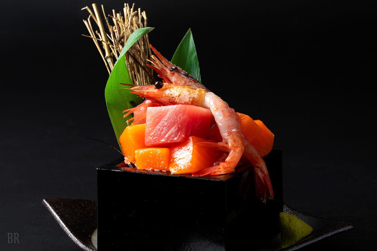 Sashimi appetizer of tuna, salmon and prawn artfully arranged on a black stand at Hotel Asafuji
