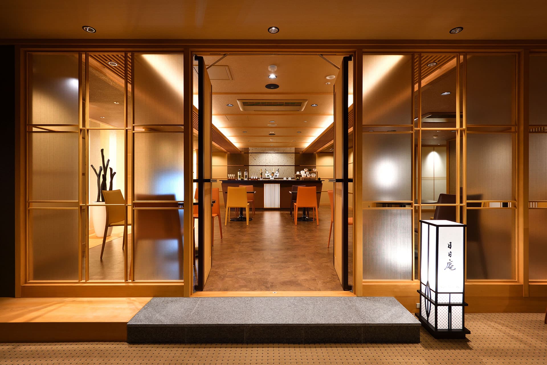Entrance to the Nichinichian dining room at Bousui with timber lattice doors, open counter seating and a paper lantern