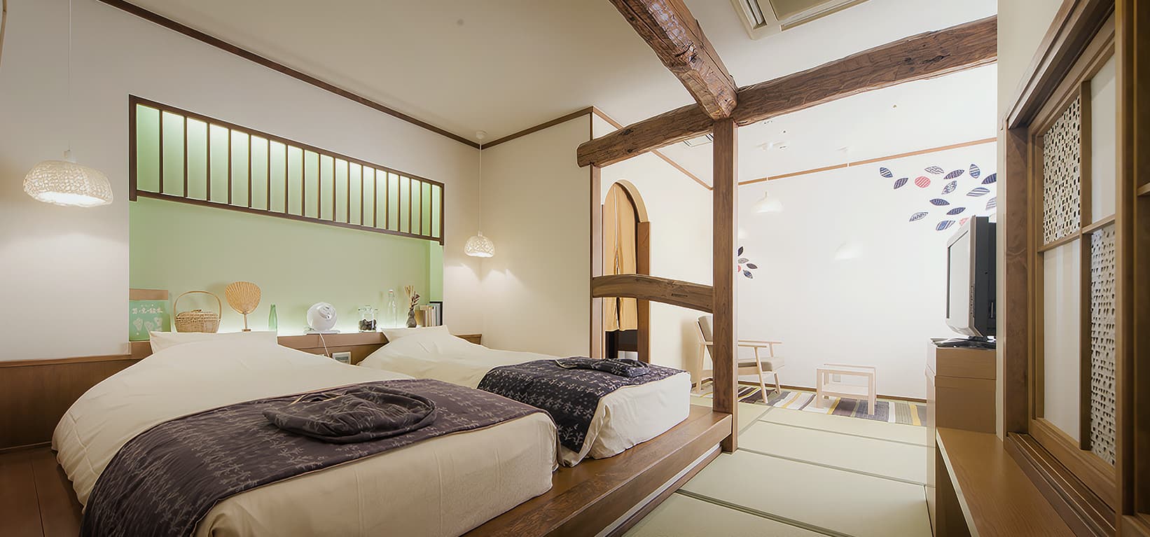 Villa guest room with twin beds beside a raised tatami lounge area at CHAHARU Hanare Dogo Yumekura, Dogo Onsen