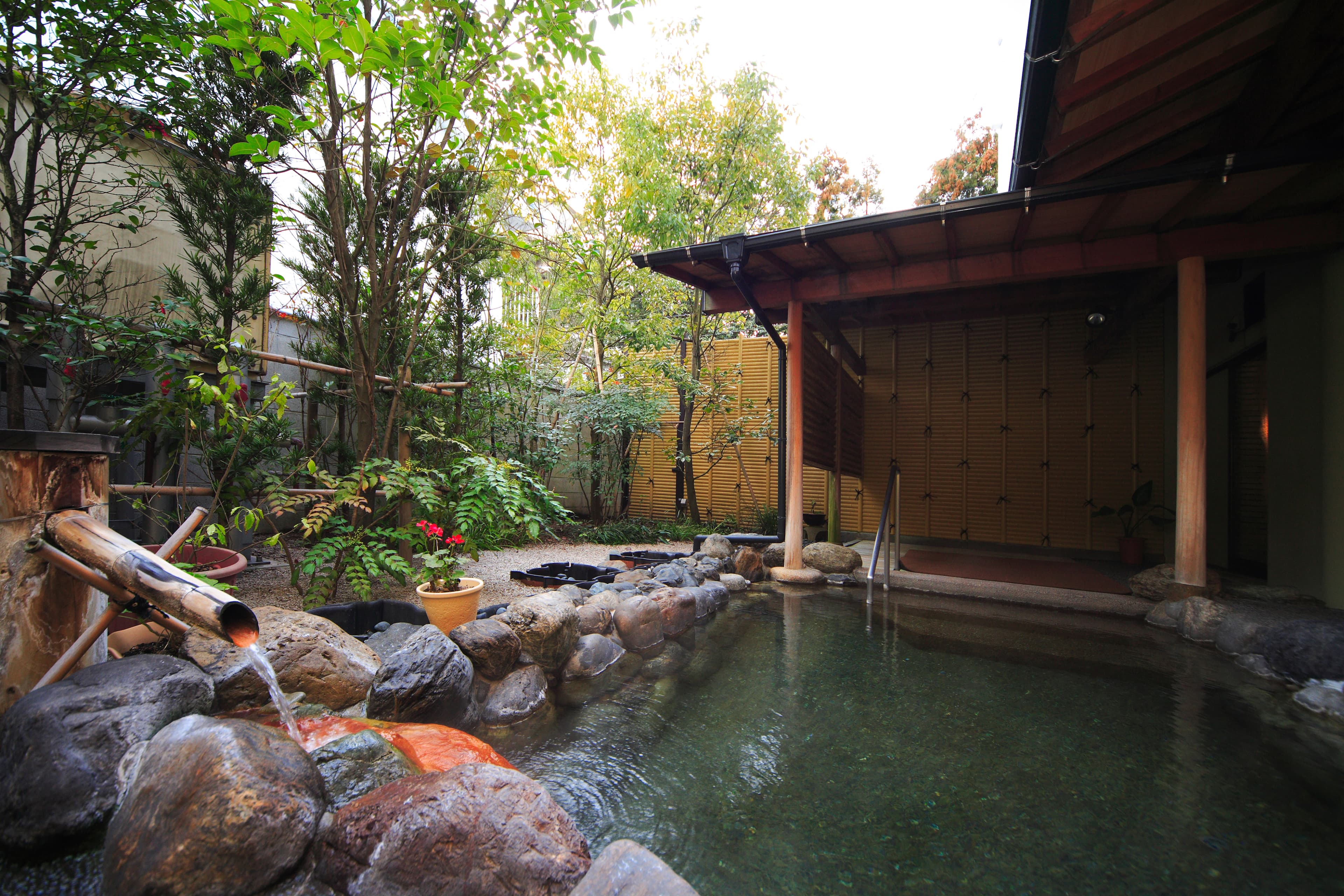 Open-air rotenburo bath surrounded by garden rocks and greenery at Yujin Chiyonoyu, Tamatsukuri Onsen, Shimane