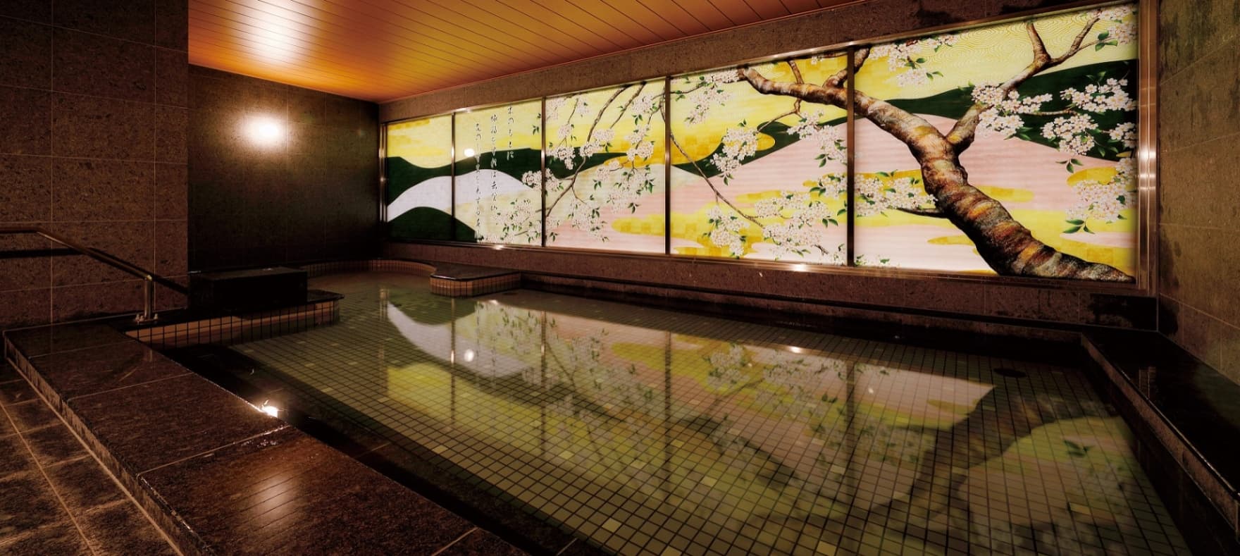 Indoor natural hot spring bath at Nara Onsen Wakakusanoyu with an illuminated cherry-blossom mural and reflective stone tub