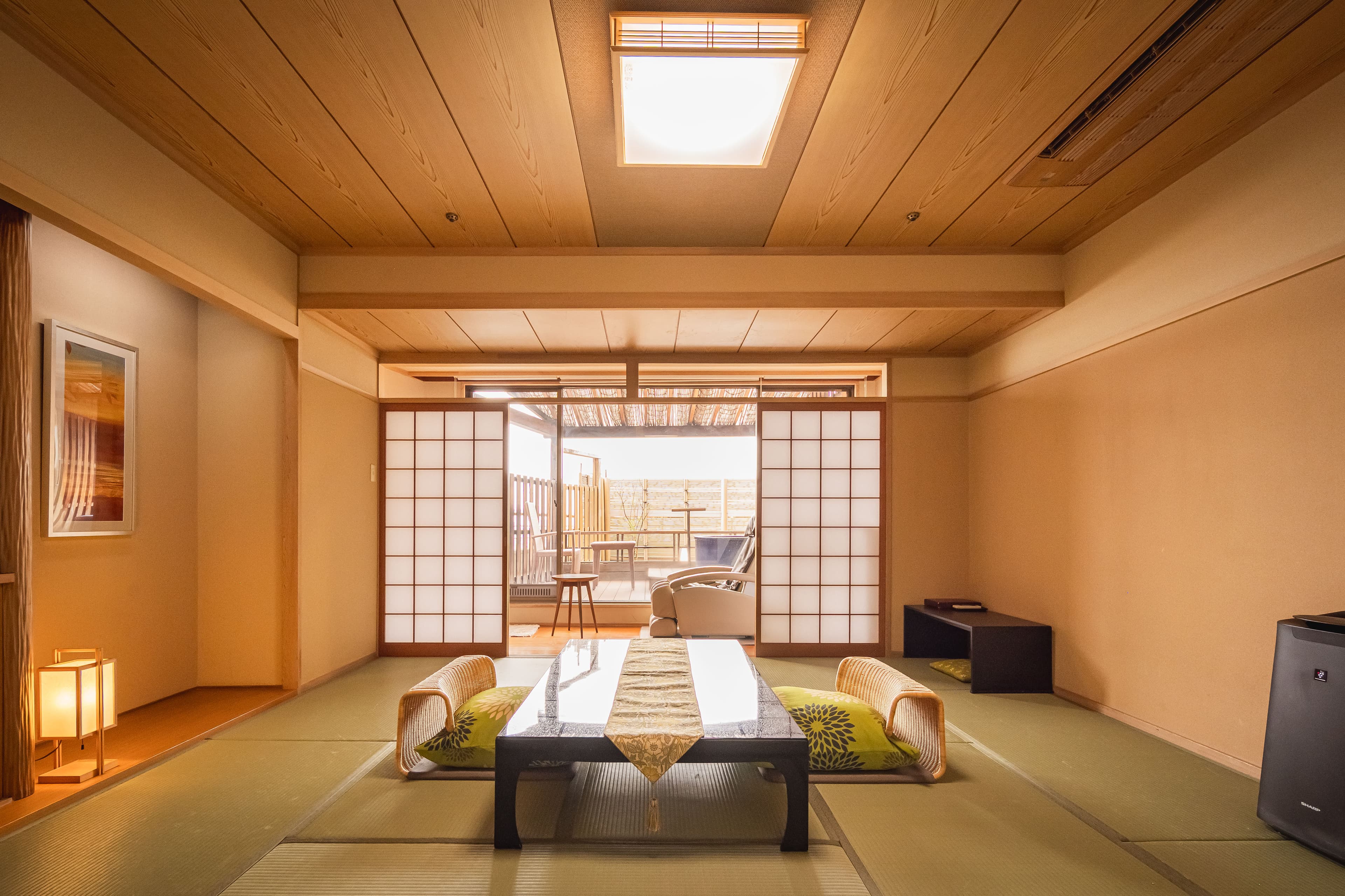 Spacious tatami guest room at Dogo Prince Hotel with low table, floor cushions and a private balcony beyond the shoji screens