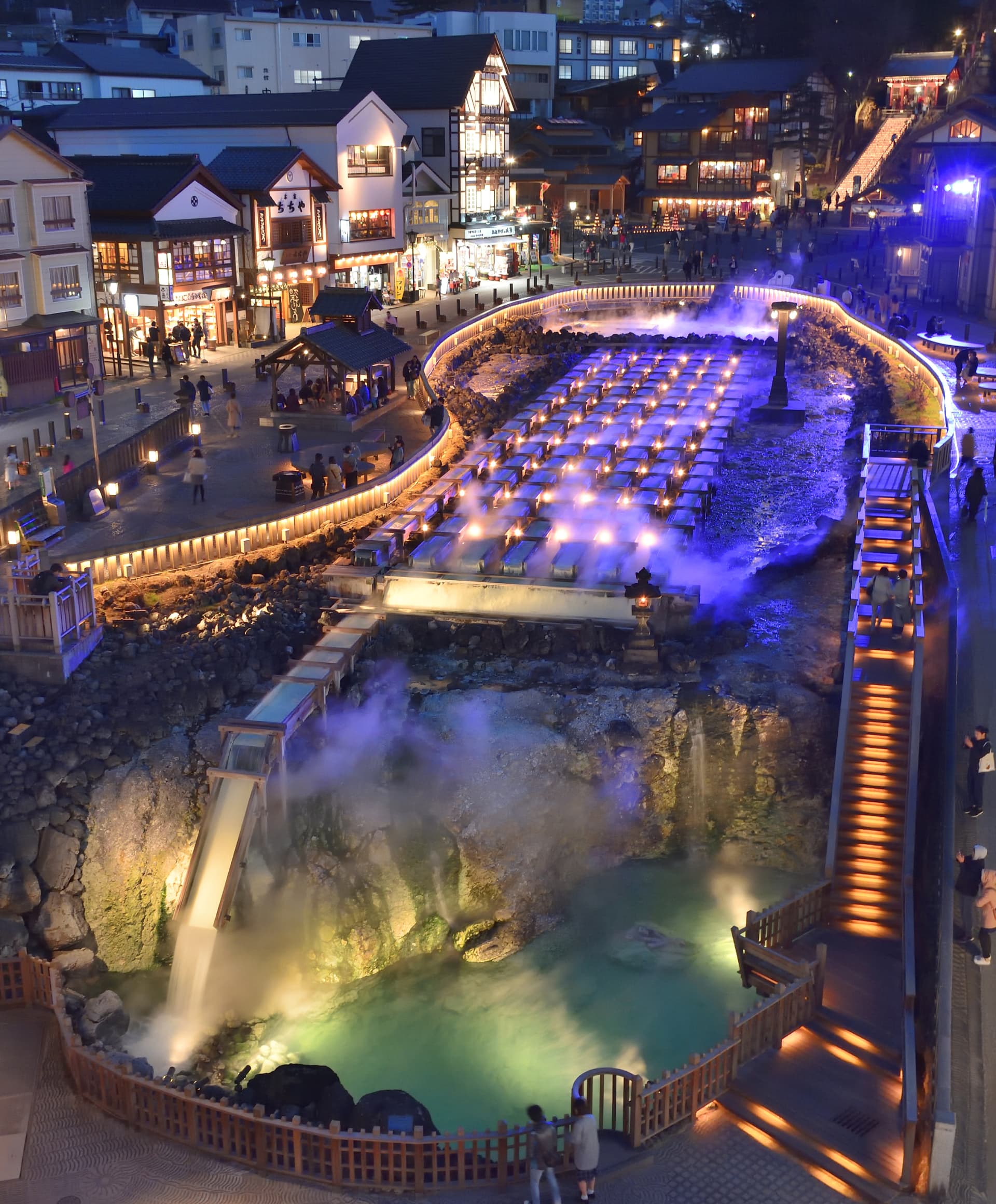 Kusatsu Onsen Yubatake hot water field illuminated at dusk with steam rising over the wooden channels