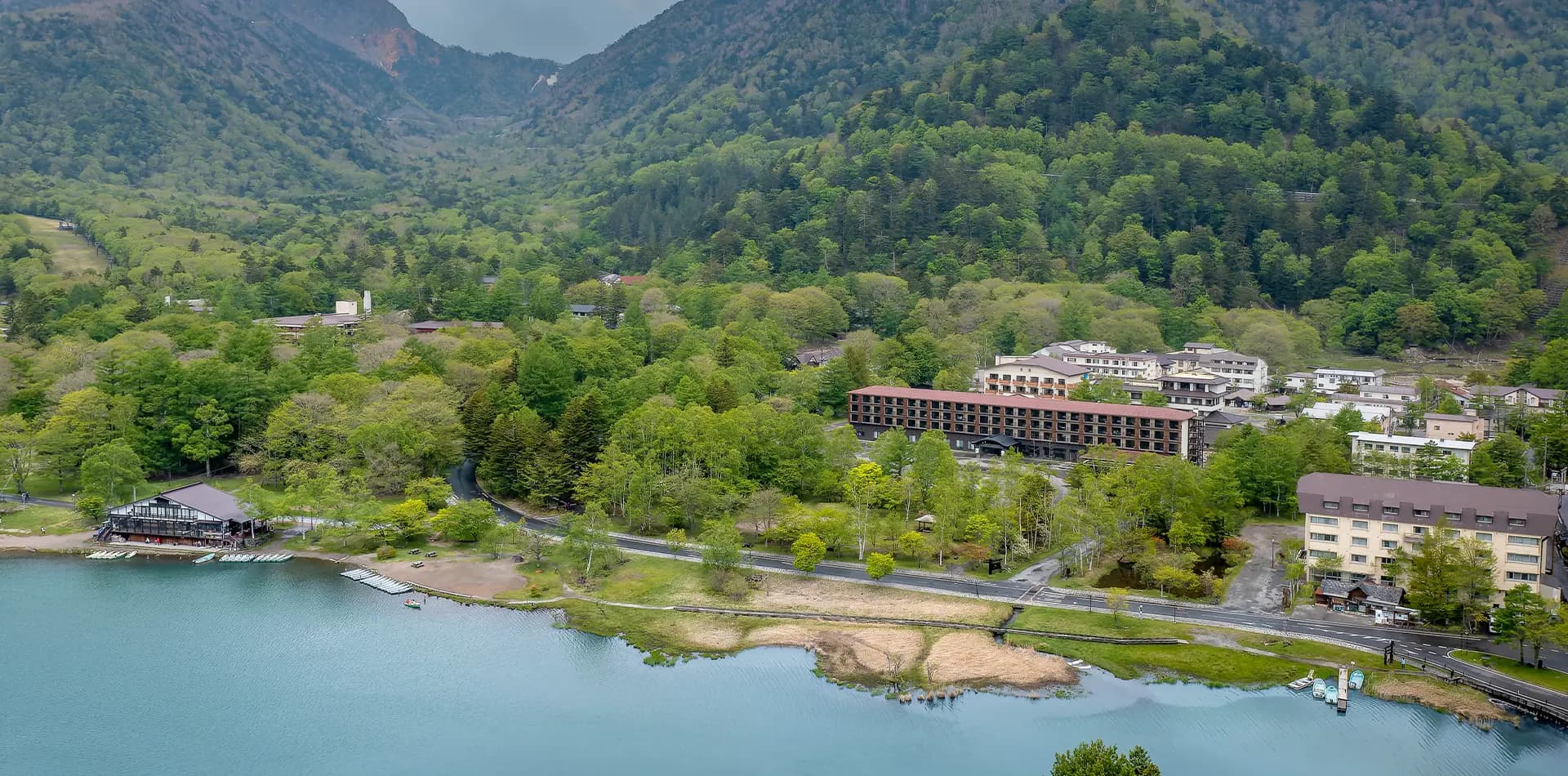 Aerial view of Kamenoi Hotel Okunikko-Yumoto set among forested mountains beside Lake Yunoko in Okunikko, Nikko