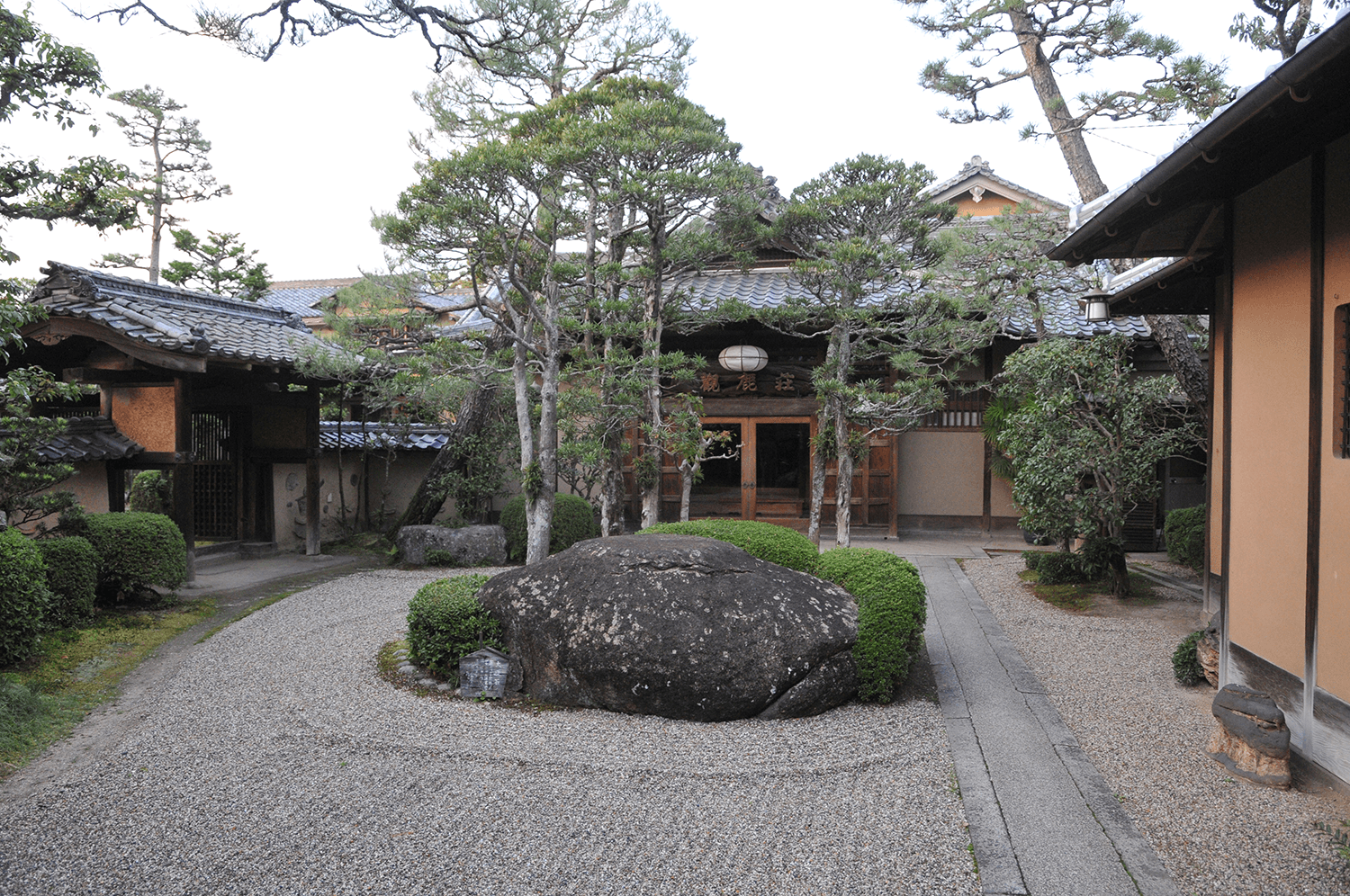 Kankaso ryokan entrance in Nara, a traditional tiled-roof wooden building behind a raked-gravel garden with pines
