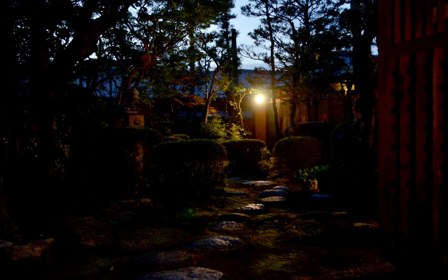 Stone-lantern-lit Japanese garden at dusk at Kankaso ryokan near Todaiji in Nara, stepping stones leading through moss and clipped shrubs