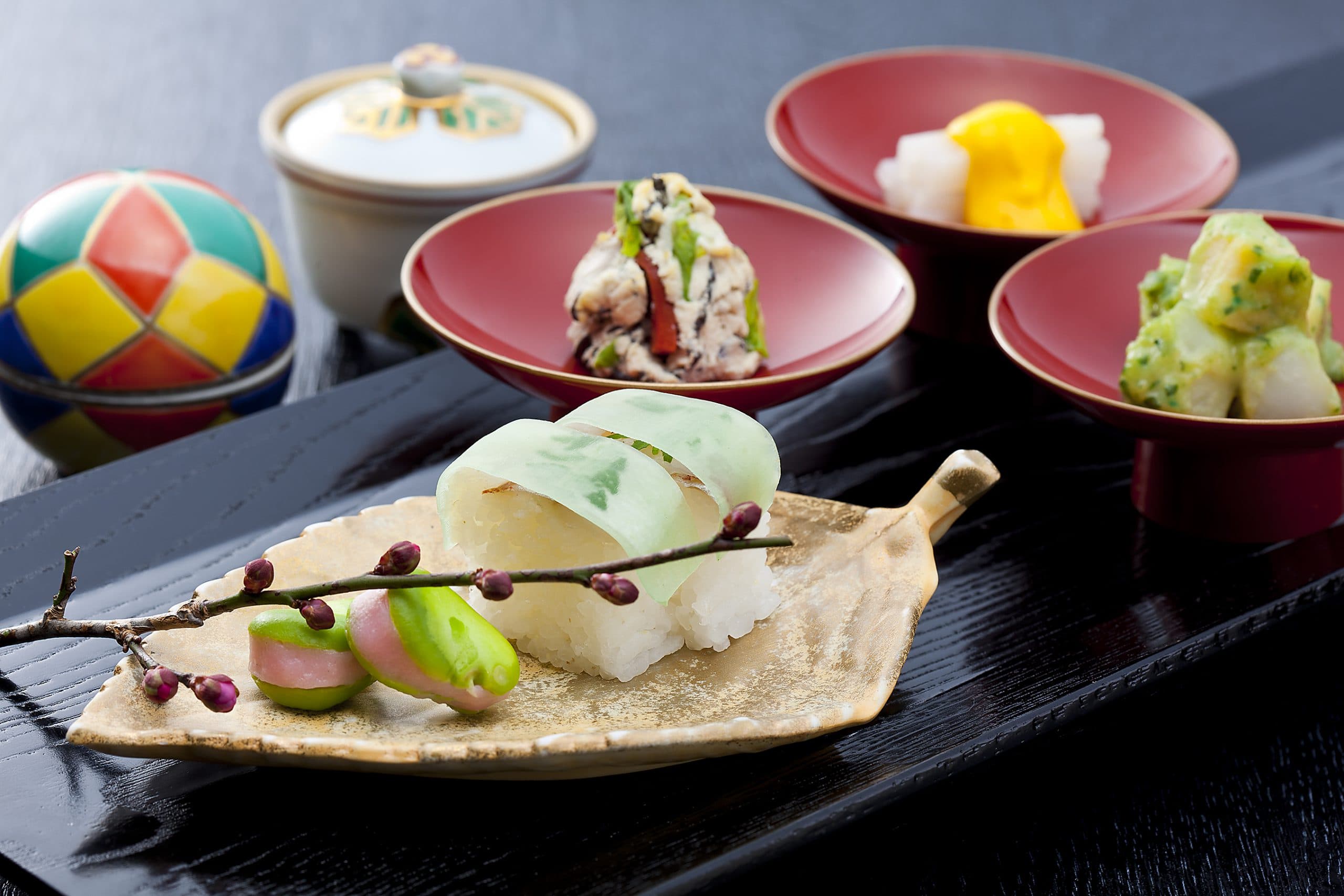 Seasonal spring kaiseki appetizer course at Kinzan plated on a leaf-shaped dish with a temari ball and small lacquer bowls