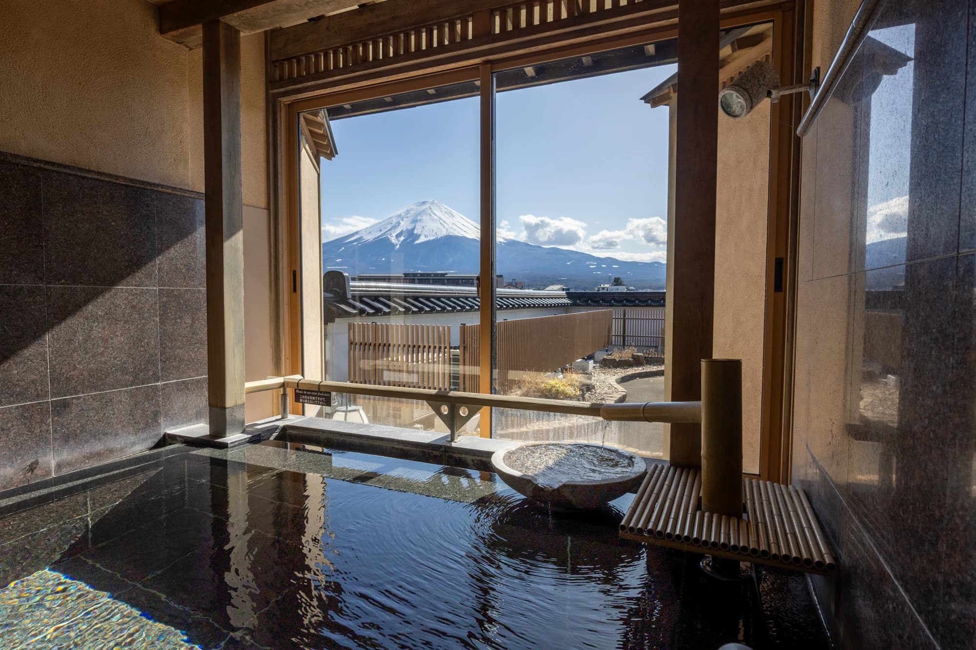 Private open-air stone onsen bath at Konansou overlooking Lake Kawaguchi with Mt. Fuji beyond
