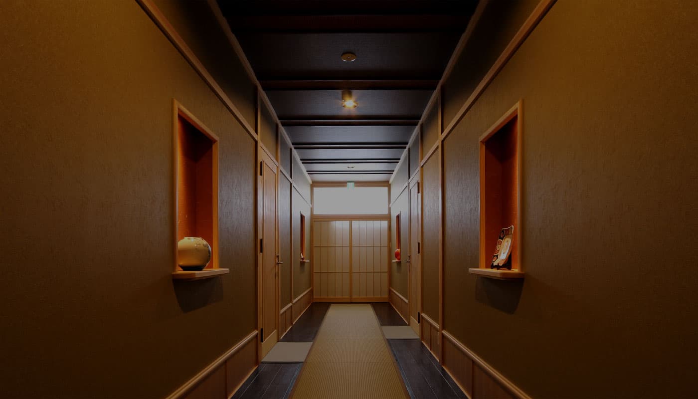 Dimly lit tatami corridor with wooden display alcoves and ceramics inside a traditional Kusatsu onsen inn