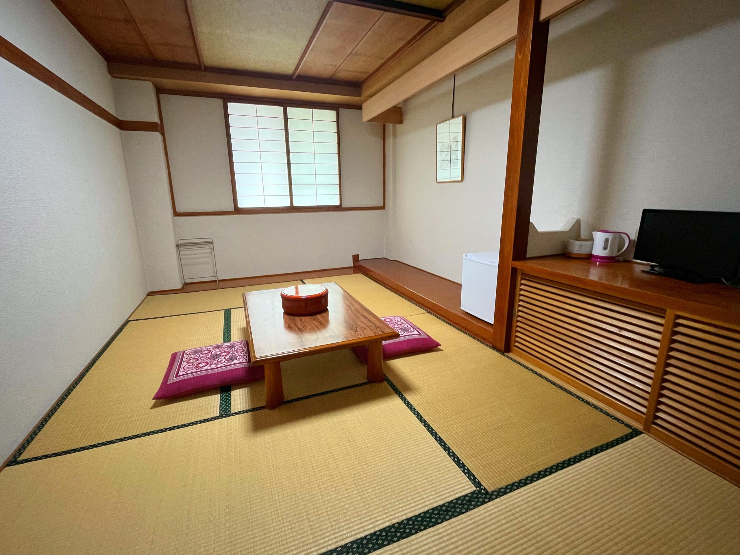 Tatami guest room with low table and engawa garden-view windows at Matsunoki-tei in Hakuba