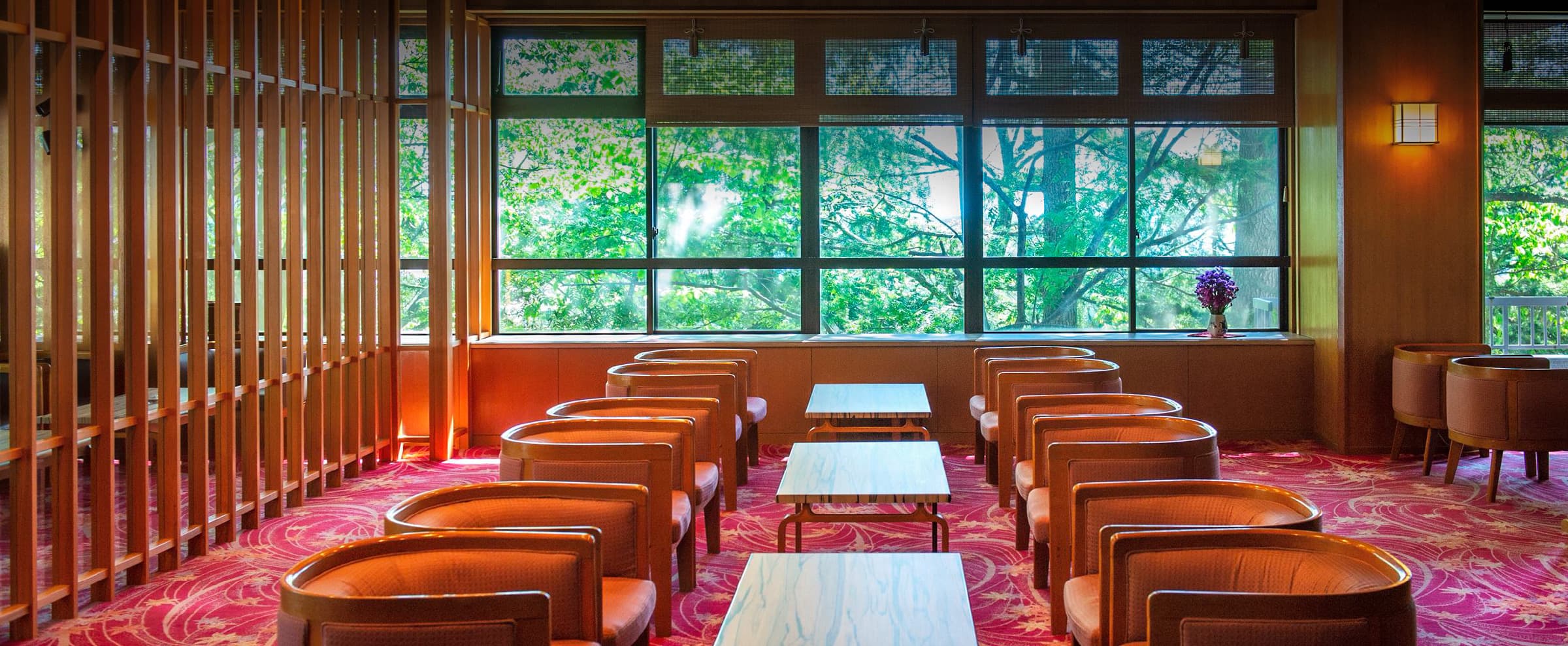 Lobby lounge with leather armchairs and floor-to-ceiling windows framing green foliage at Meitoya So