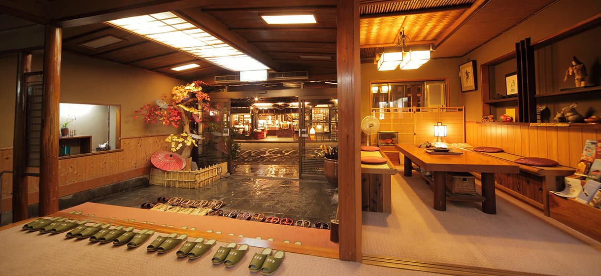 Morizuya ryokan entrance genkan in Kinosaki Onsen with rows of guest geta sandals, sunken garden and warm wood interior