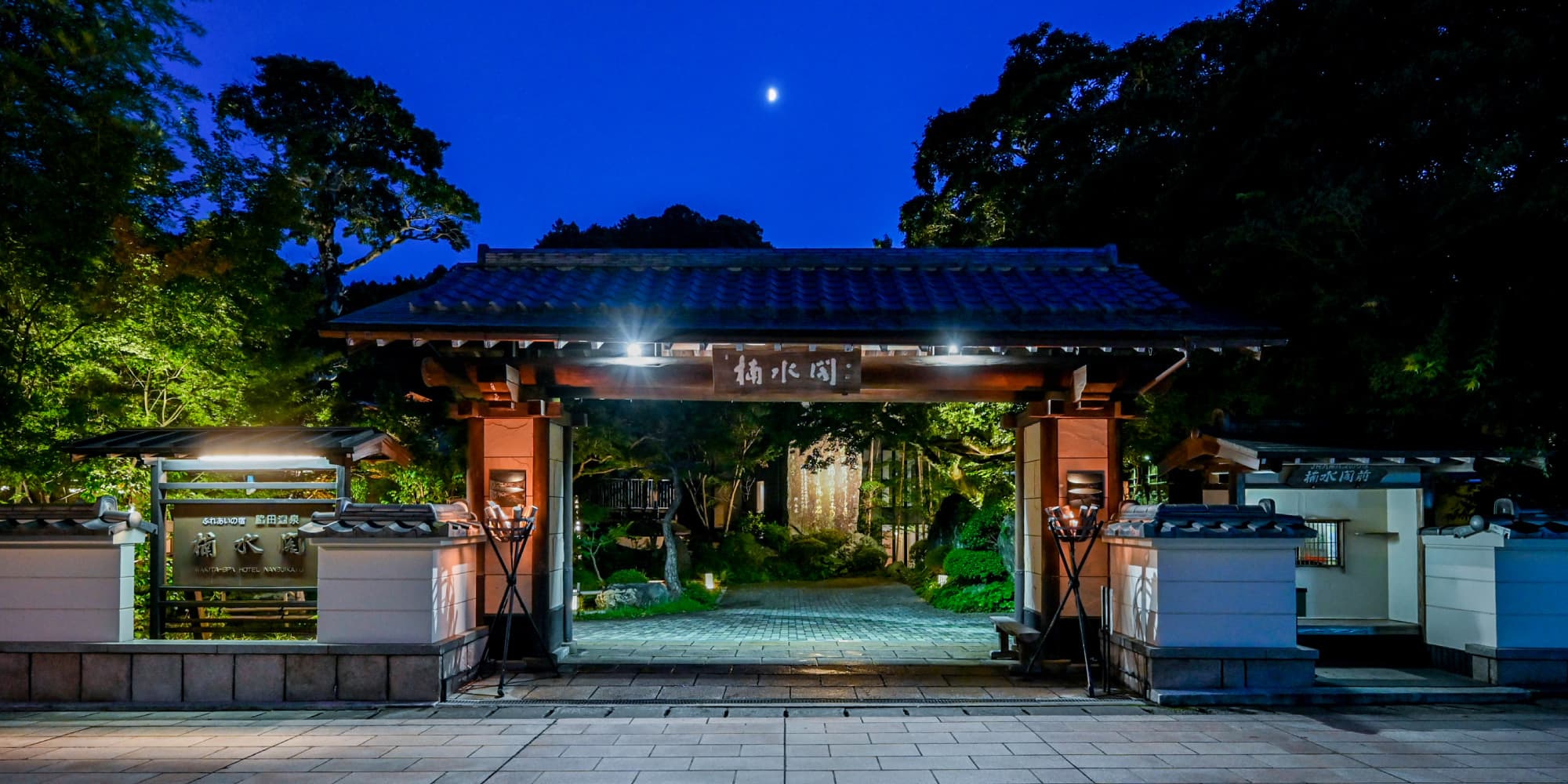 Illuminated traditional wooden entrance gate of Nansuikaku at night under a moonlit sky