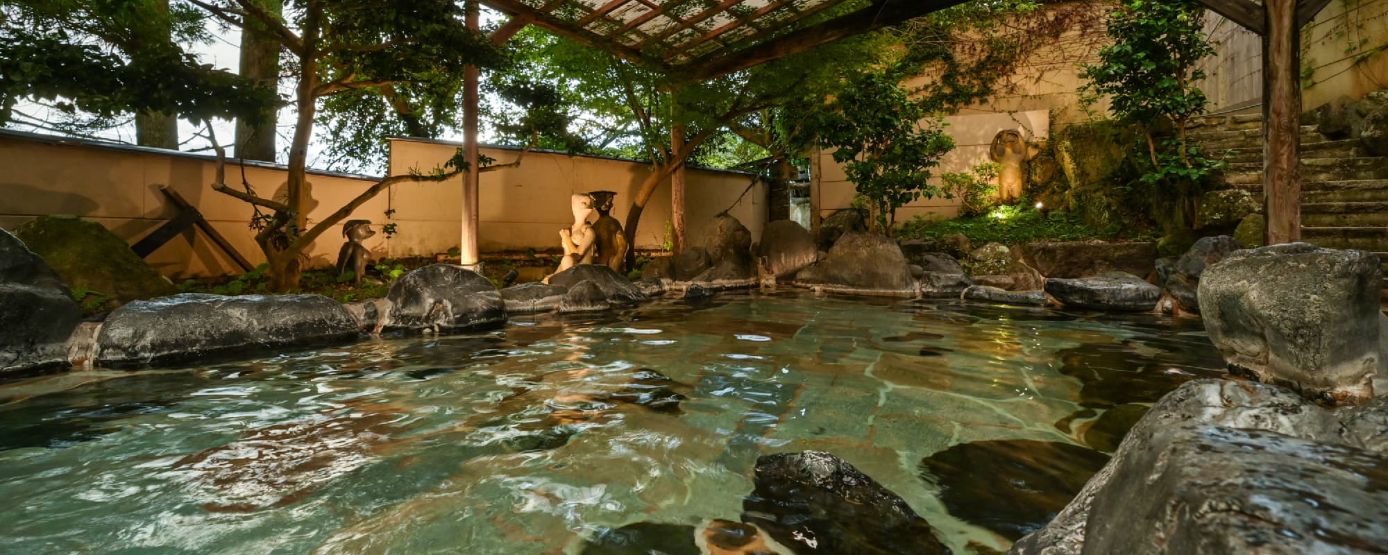 Garden rotenburo at Nansuikaku set among natural rocks, trees and stone statues