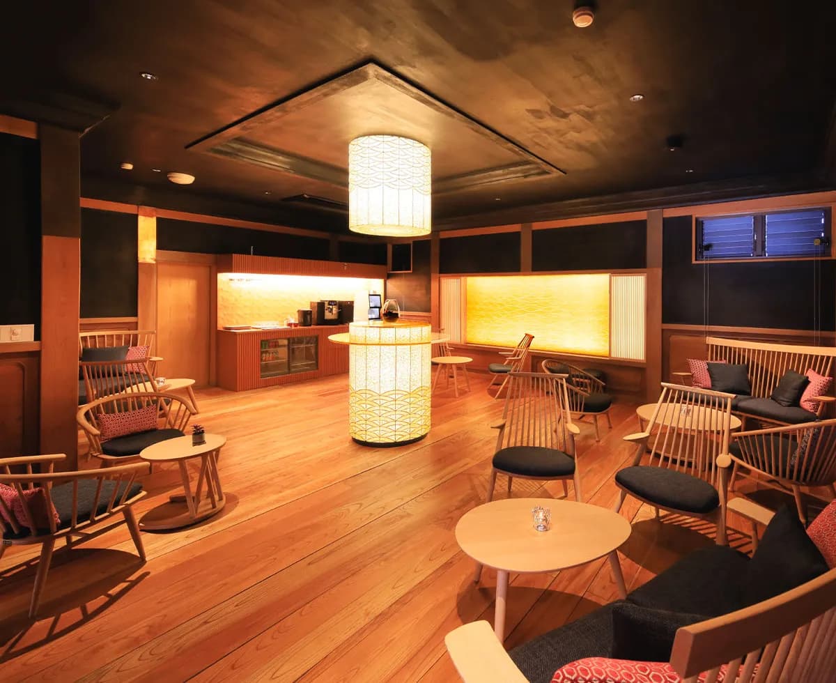 Cedar-floored guest lounge and free-drink corner with Japanese lattice lighting at Fuji Onsenji Yumedono