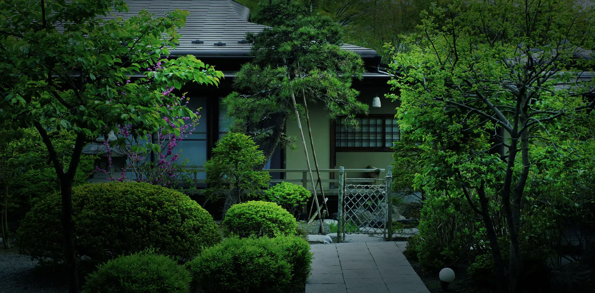 Fuji Onsenji Yumedono traditional wooden main building behind a manicured Japanese garden with flowering trees