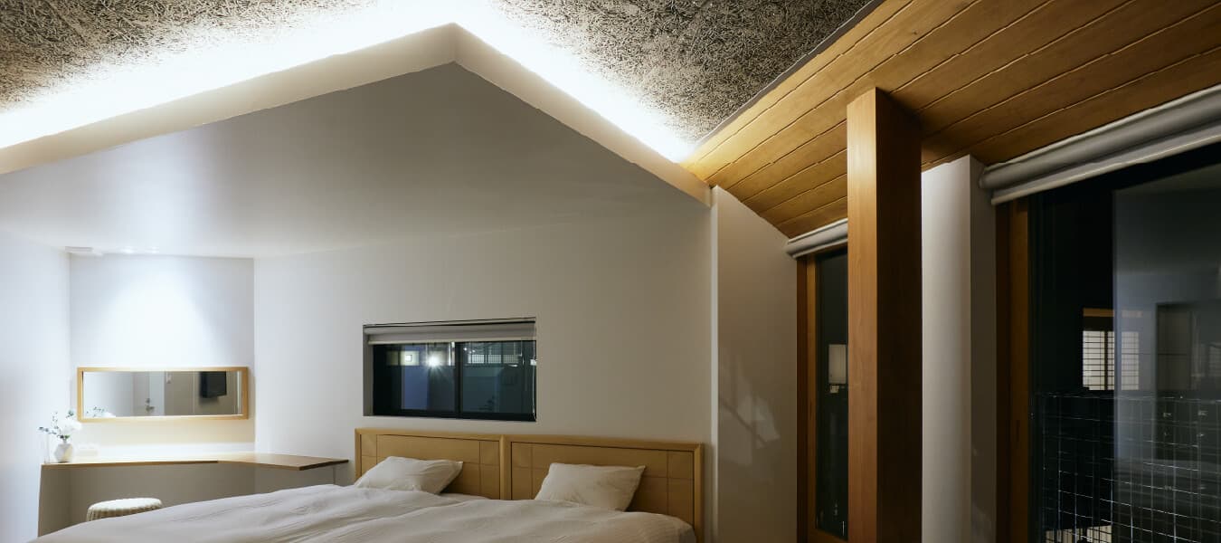 Modern guest room at Tsuchiya with twin beds under a vaulted plaster ceiling and indirect lighting