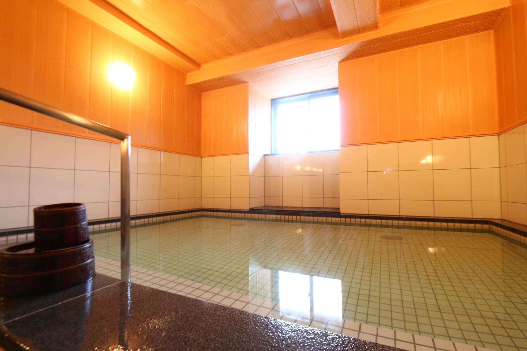 Indoor hot-spring bath at Ryokan Murayama with cypress-panelled walls and clear Takayama onsen water