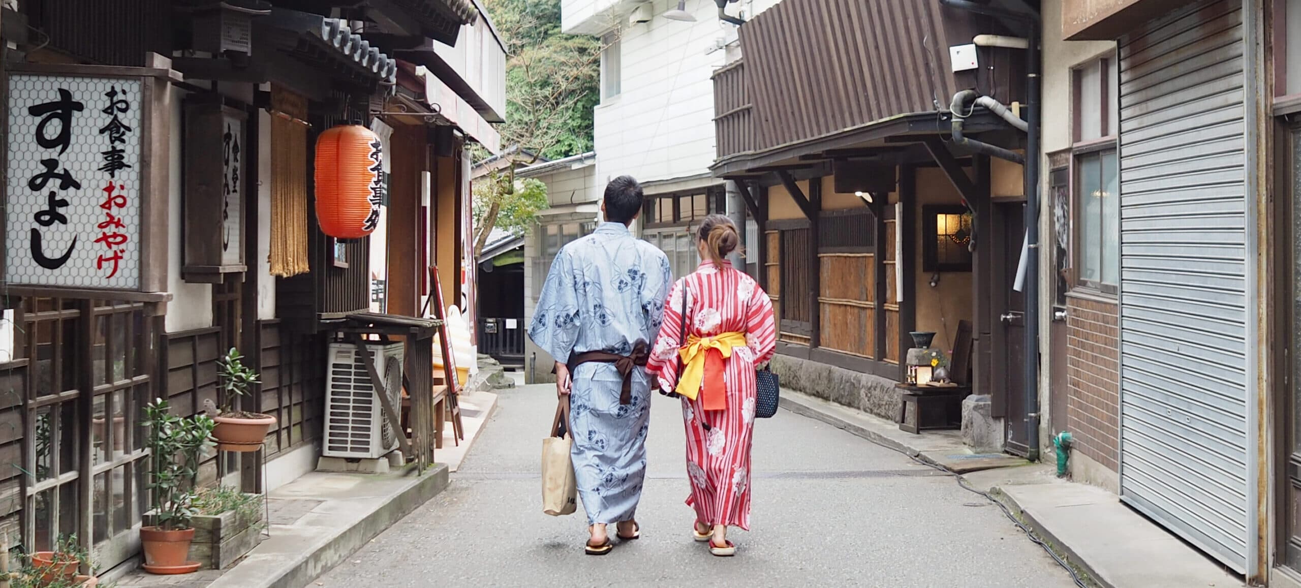 Couple in yukata strolling the historic Kurokawa Onsen lane near Ryokan Wakaba