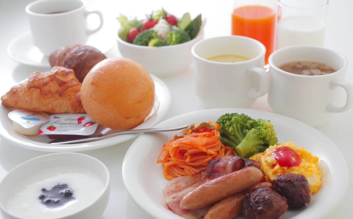 Western breakfast plate at Spa Hotel Alpina with scrambled eggs, sausages, bacon, croissants, salad and juices