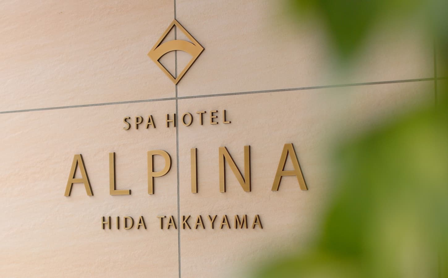 Gold SPA HOTEL ALPINA Hida Takayama lettering and emblem mounted on the hotel's entrance wall
