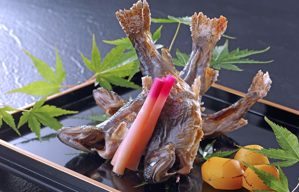 Salt-grilled river fish presented on a lacquered tray with maple leaves