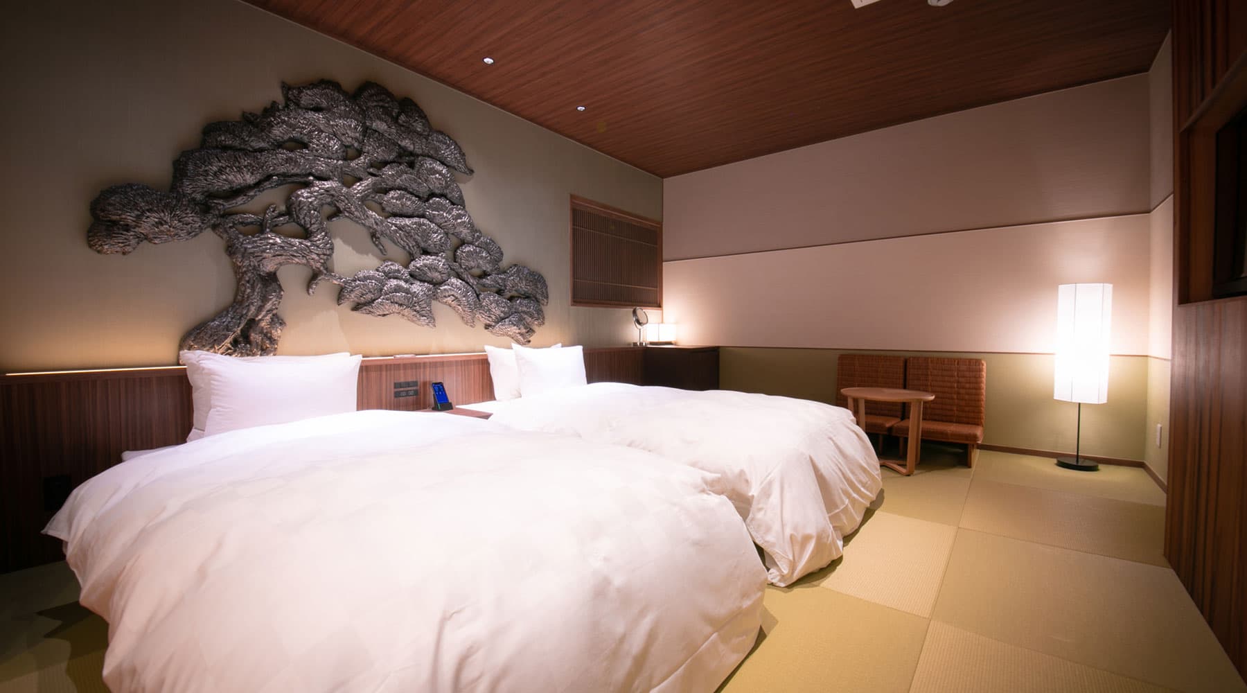 Tokitotoki suite bedroom with twin beds beneath a sculpted silver pine-tree wall art over tatami
