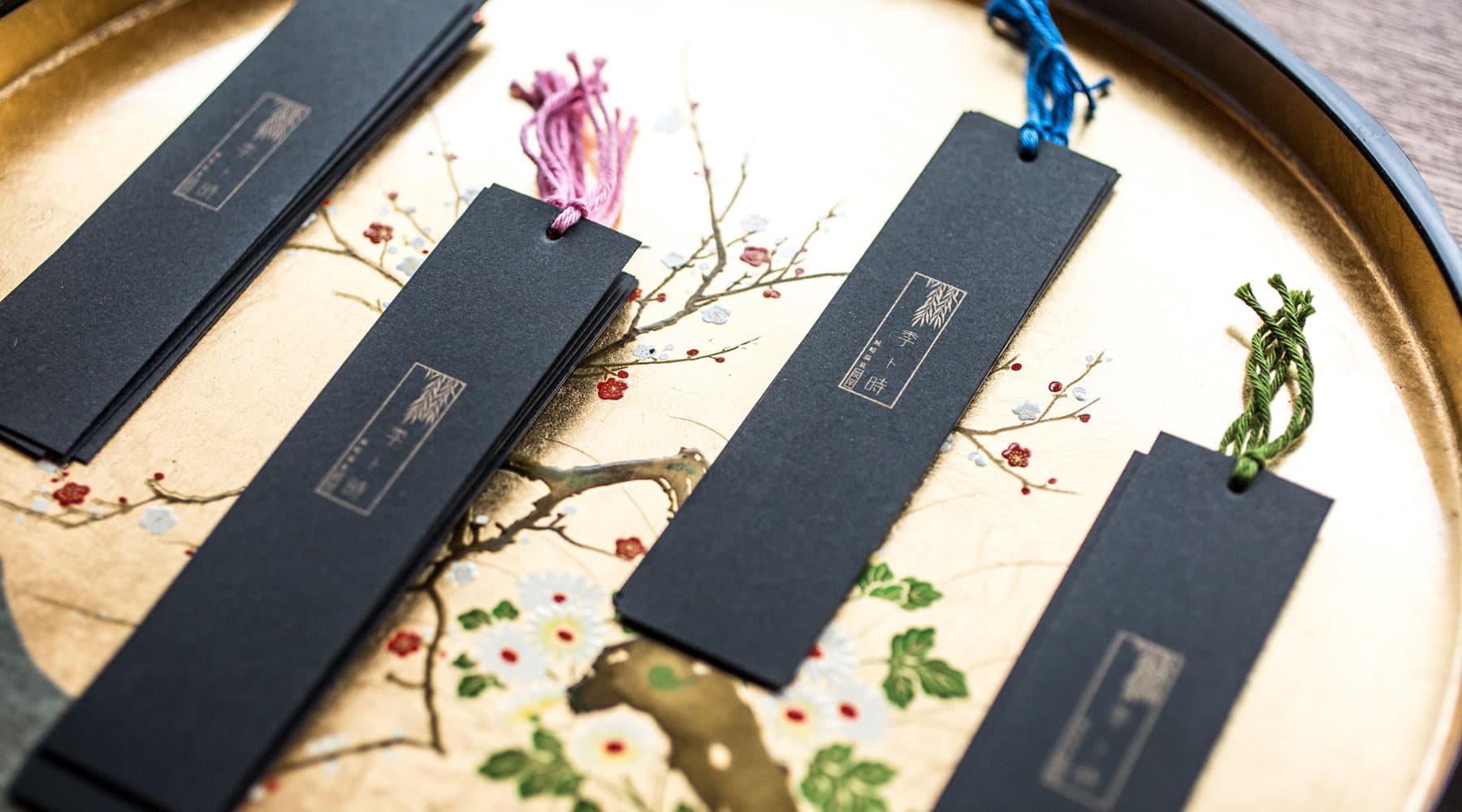 Tasseled room-name tags resting on a gold floral lacquer tray at Tokitotoki