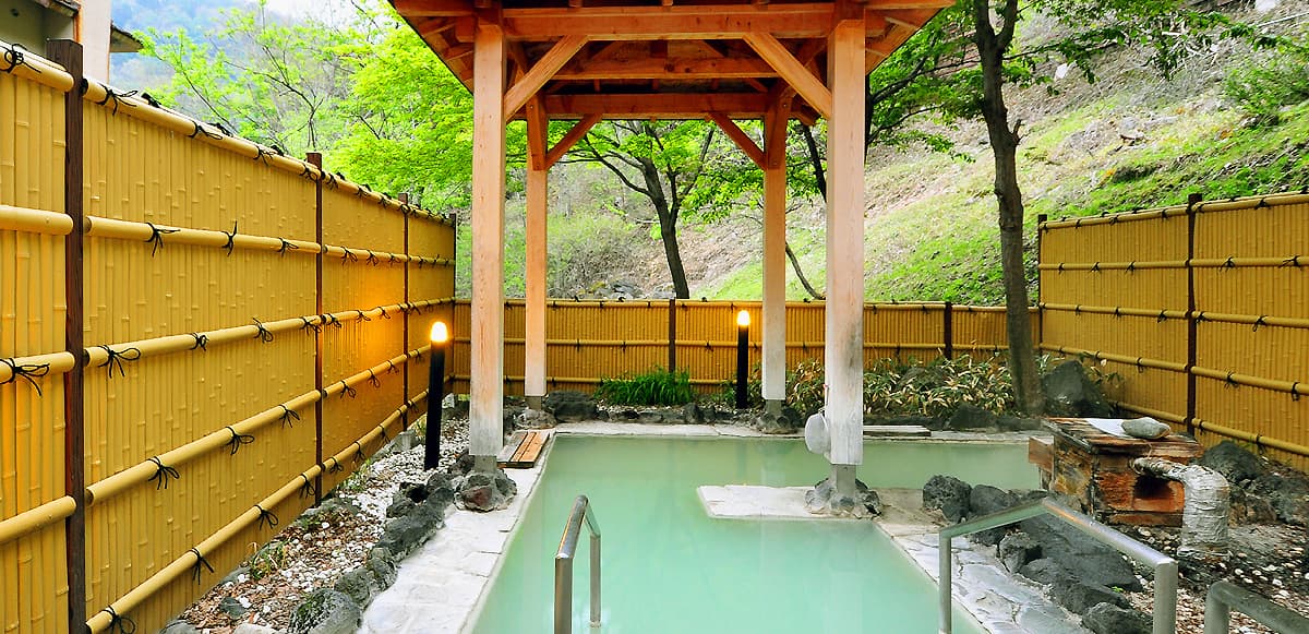 Open-air sulfur rotenburo with milky hot-spring water and bamboo fence at Yumoto Itaya, Okunikko Yumoto Onsen