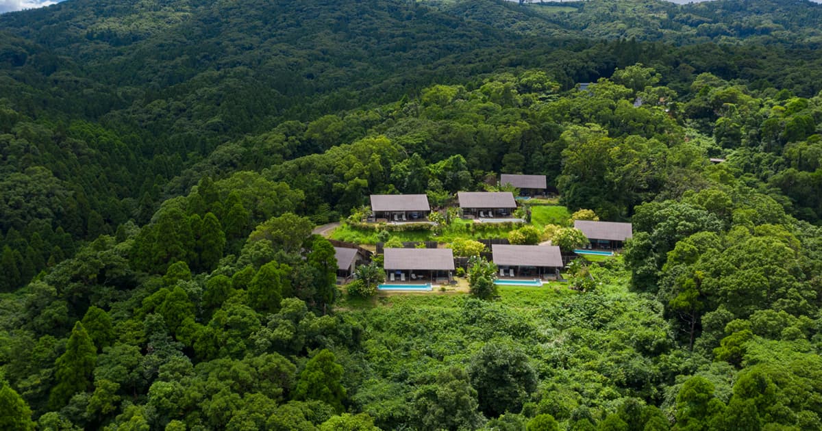 Aerial view of Yurian's thatched detached villas set amid lush green hills above Ibusuki Onsen, Kagoshima