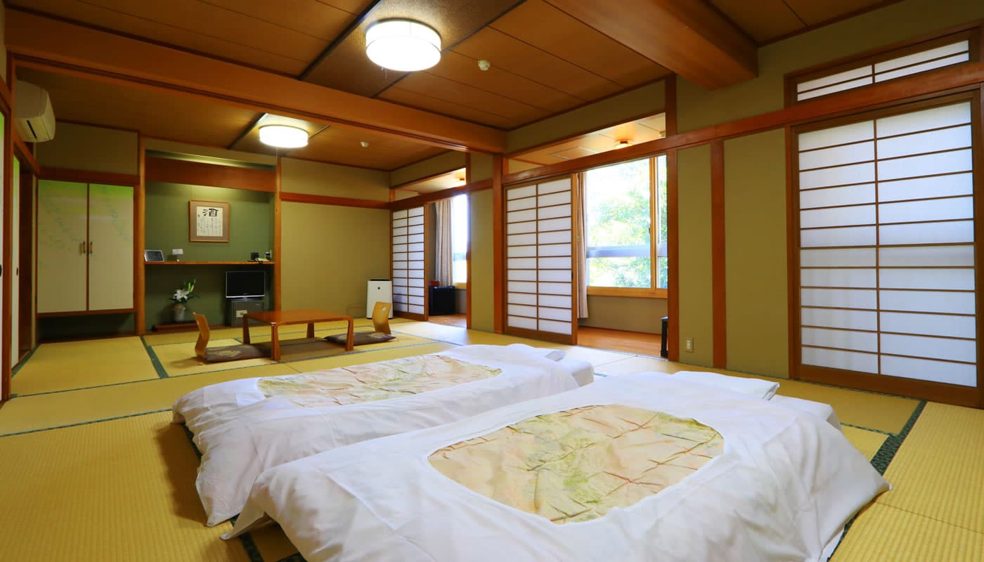 Spacious Japanese-style tatami guest room with futons laid out and a garden view at Yamaichi Bekkan on Miyajima island