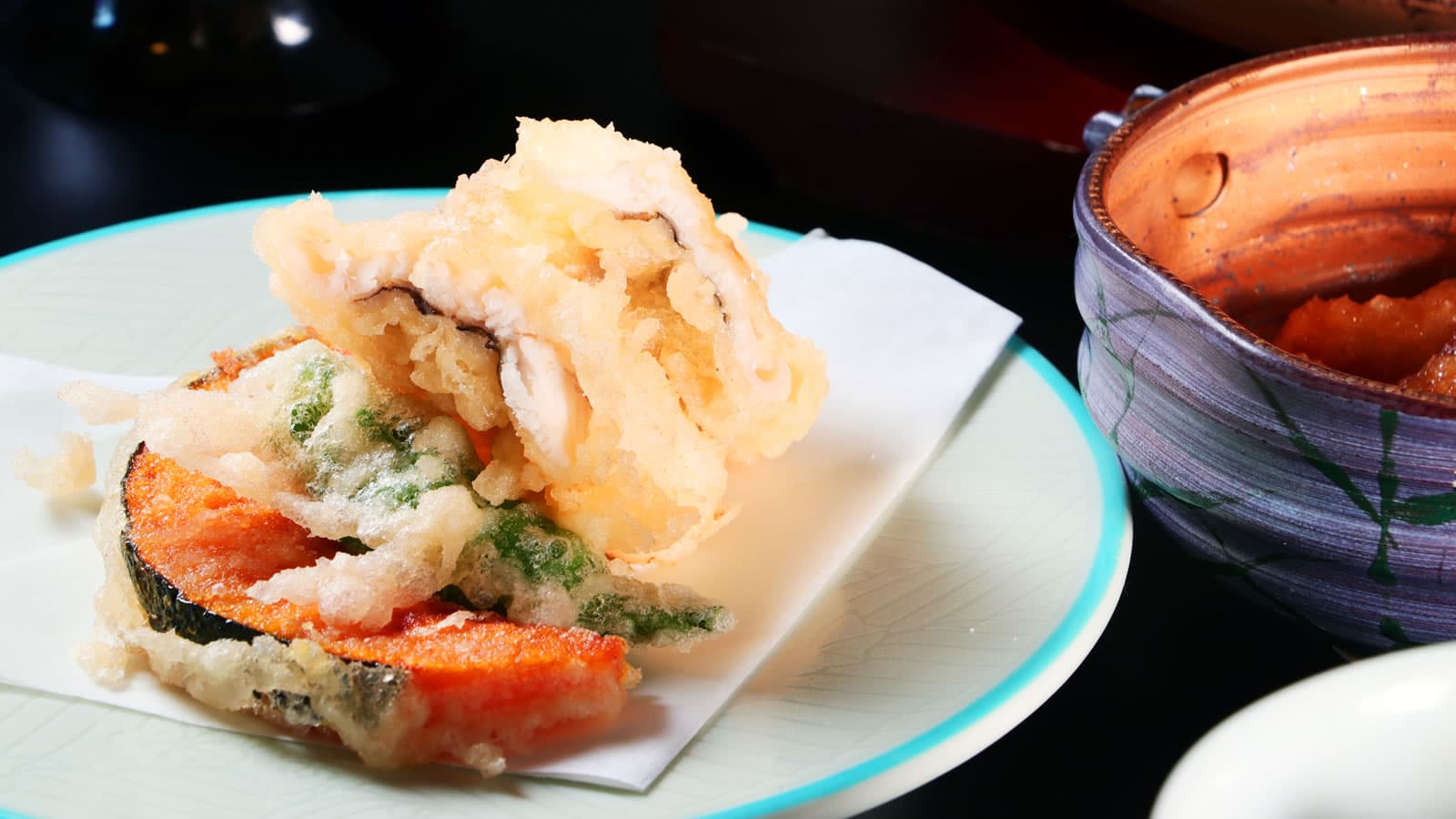 Freshly fried seasonal vegetable and seafood tempura served on a ceramic plate at Yamaichi Bekkan, Miyajima