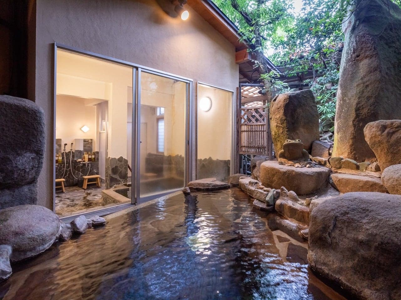 Open-air stone rotenburo bath surrounded by boulders and greenery at Yumoto Tamaikan, Tamatsukuri Onsen